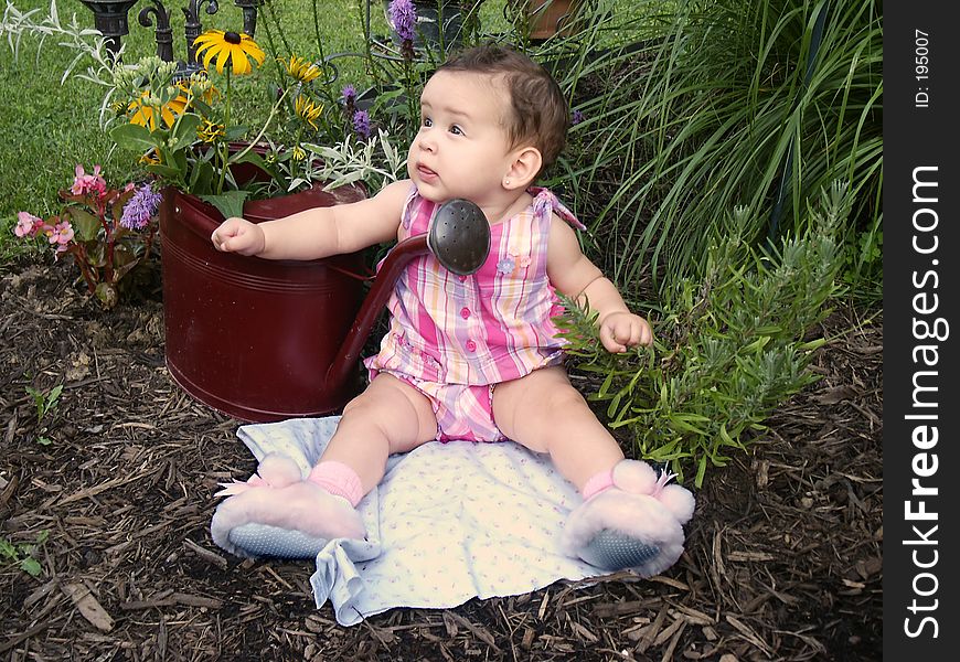 Baby in garden with watering can planter