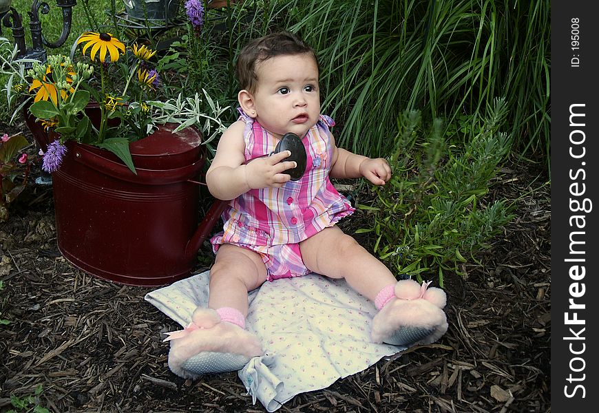 Baby on blanket by watering can with flowers. Baby on blanket by watering can with flowers