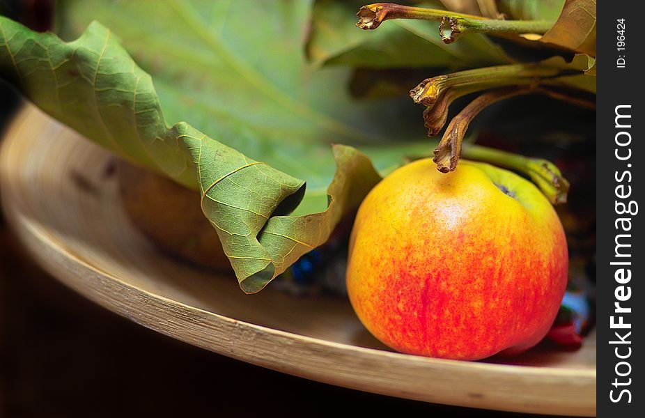 A plate with an apple and leaves. A plate with an apple and leaves