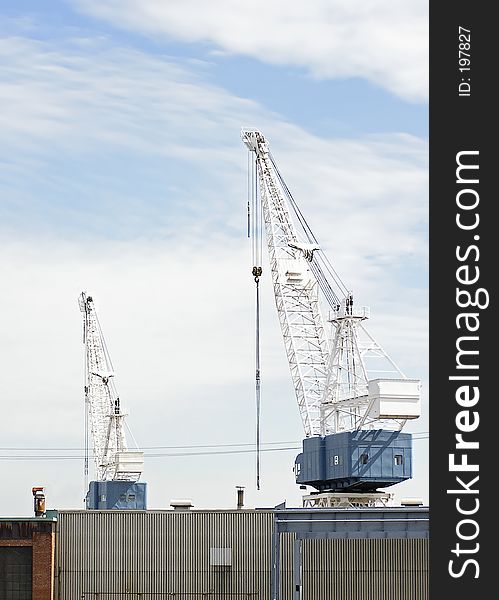 White construction cranes on a cloudy blue sky. White construction cranes on a cloudy blue sky