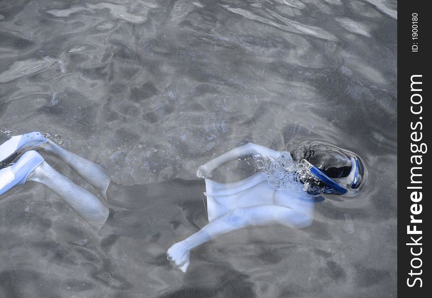 Young man snorkelling, deep blue filter