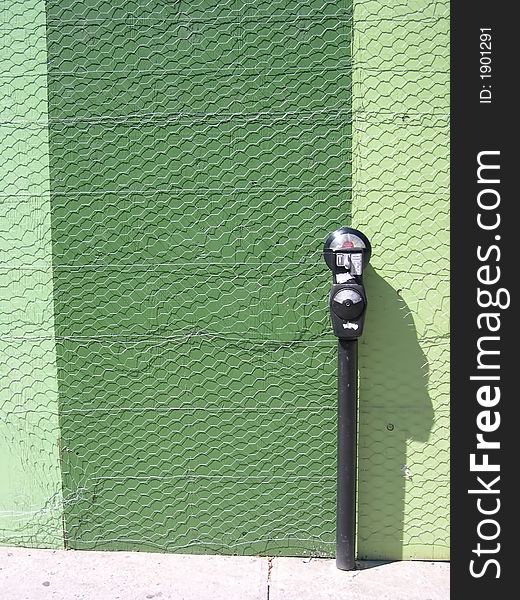 A parking meter set against a green backdrop. A parking meter set against a green backdrop.