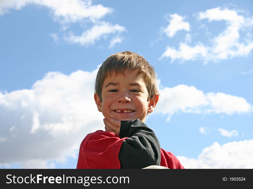 Boy smiling with the clouds in the background. Boy smiling with the clouds in the background