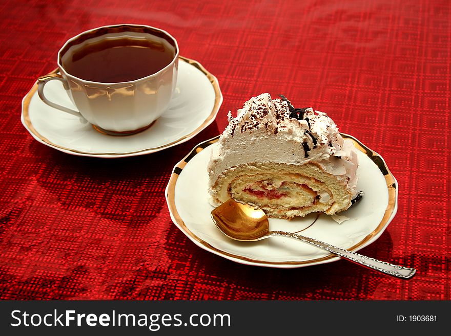 Cup of tea with the spoon and a slice of pie on red background