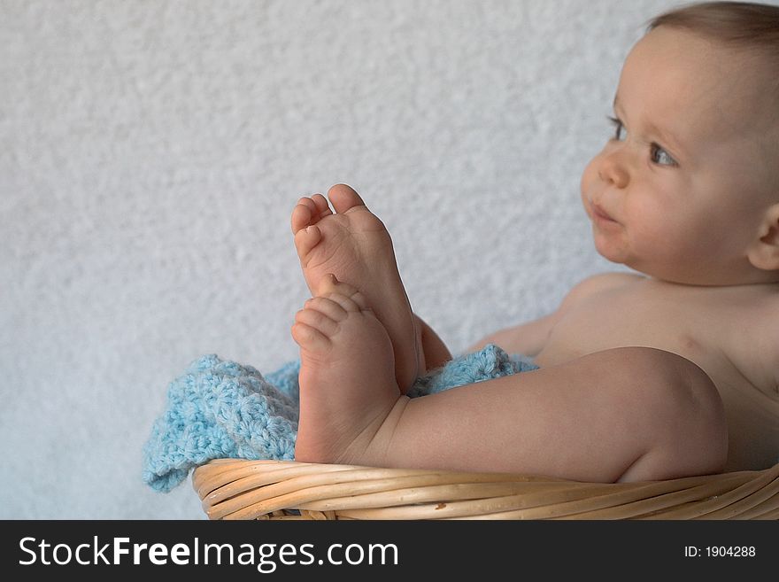 Image of baby sitting in a blanket-lined basket. Image of baby sitting in a blanket-lined basket