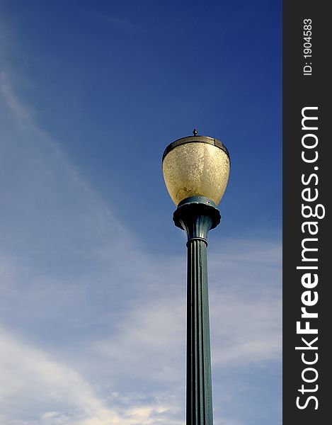 Detail of old light post with blue sky and clouds