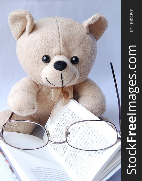 A cute little bear with glasses, reading a book. A cute little bear with glasses, reading a book