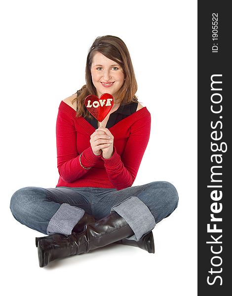 Sitting girl holding a big red 'love' lollipop. Isolated on white. Sitting girl holding a big red 'love' lollipop. Isolated on white.