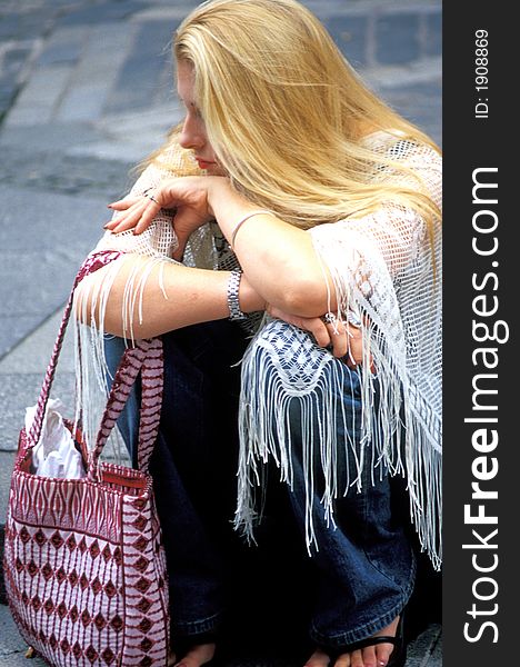 A tired female shopper relaxing on the street.