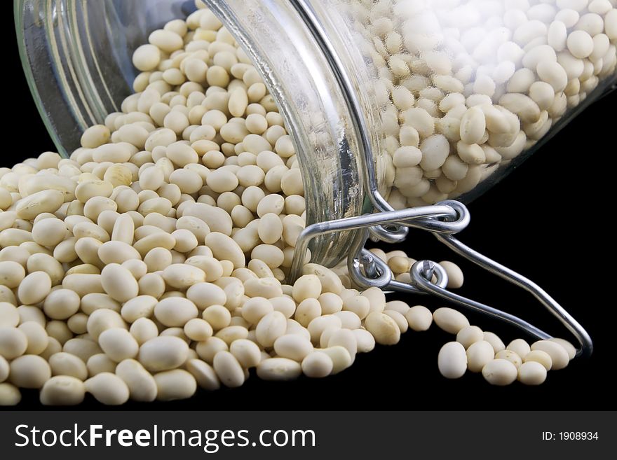 White kidney beans in a pile near open glass jar. White kidney beans in a pile near open glass jar