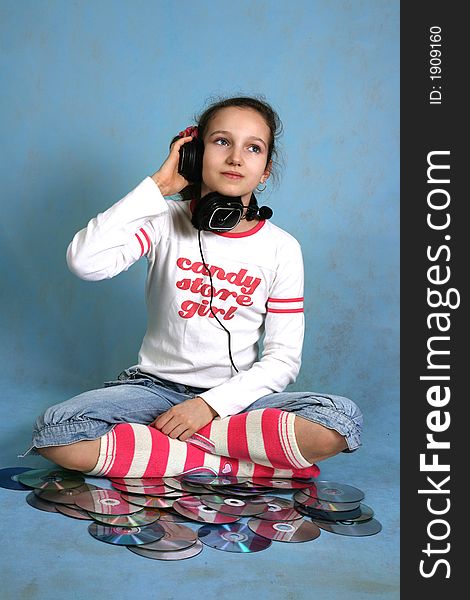 The nice girl with headphones on a head on a blue background. The nice girl with headphones on a head on a blue background