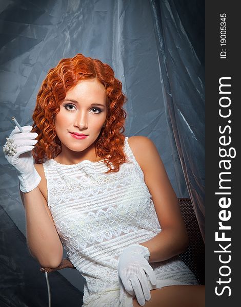 girl with beautiful red curly hair wearing white short dress and gloves holding cigarette. girl with beautiful red curly hair wearing white short dress and gloves holding cigarette