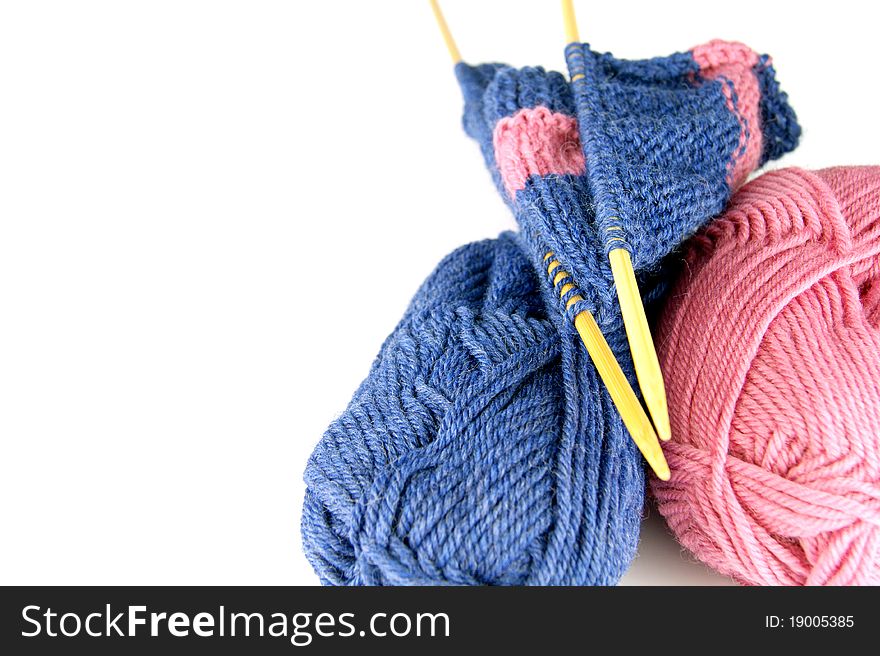 Knitting. Two balls two needles with a cloth on a white background