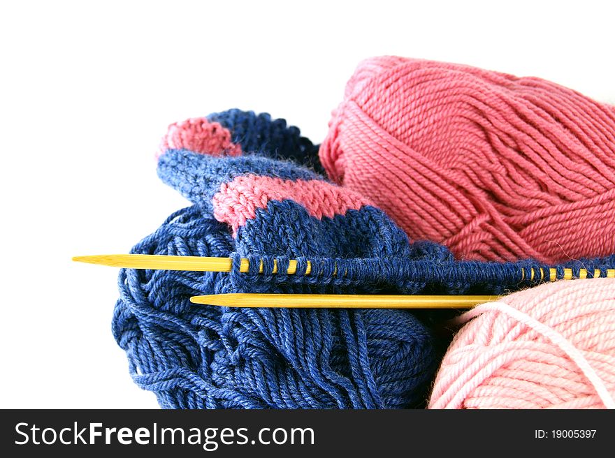 Knitting. Three balls two needles with a cloth on a white background