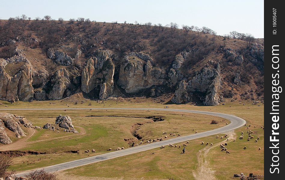 Country road with sheeps  through the rocky hills.