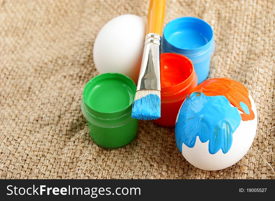 Easter eggs brush and Jars with a bright paint on a rough canvas background