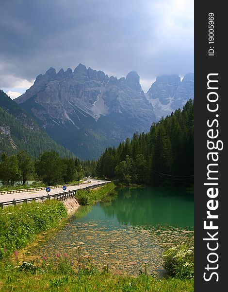 Amazing high mountains on the road in Italian alps. Beautiful nature with a clear lake and green forest. Amazing high mountains on the road in Italian alps. Beautiful nature with a clear lake and green forest.
