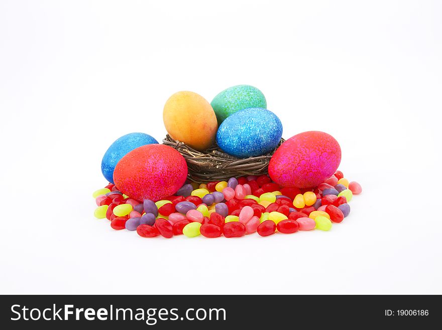 Mottle colored Easter eggs in a natural twig nest sit on colorful jelly beans. Mottle colored Easter eggs in a natural twig nest sit on colorful jelly beans