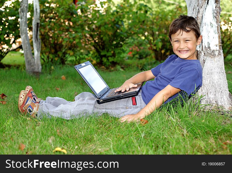 Boy with notebook sit at tree outdoors