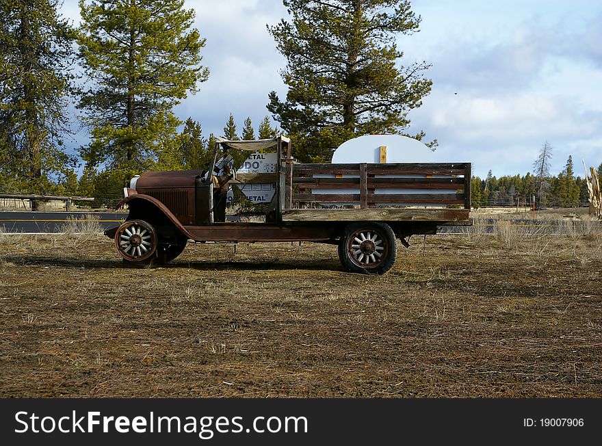 An old farm truck sitting in the middle of a pasture.