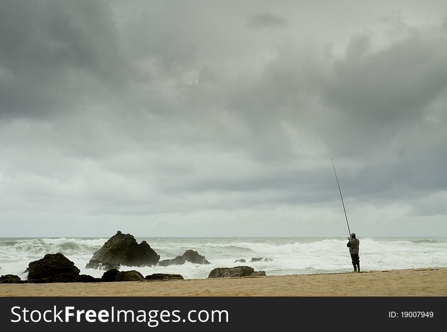 Man fising nearby stormy beach. Man fising nearby stormy beach