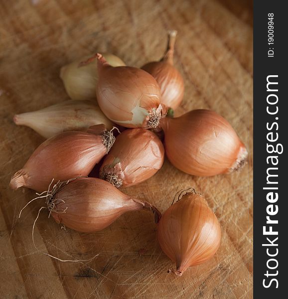 Baby onions grouped together on a chopping board, ready for preparation to cook.