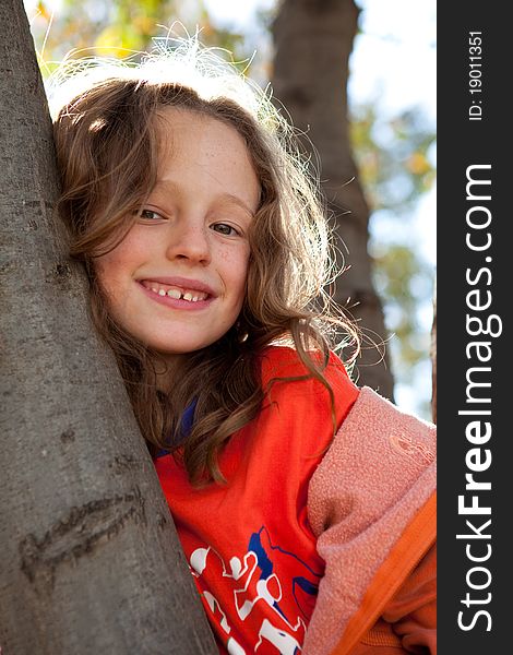 Pretty young girl climbing tree and smiling. Pretty young girl climbing tree and smiling