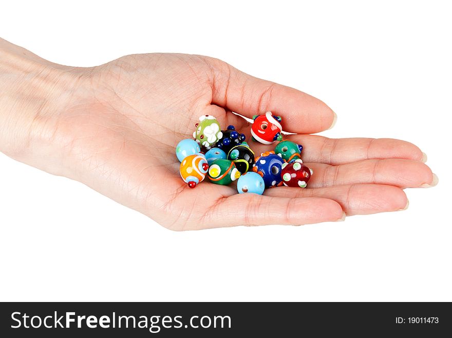 Colored glass beads in a female hand on a white background