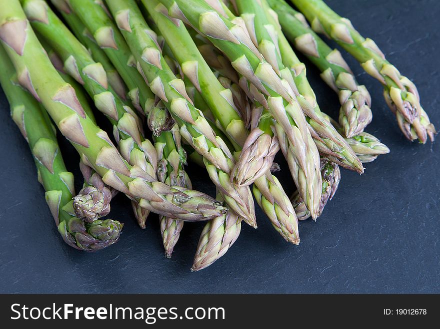 A selection of raw asparagus spears on a slate platter