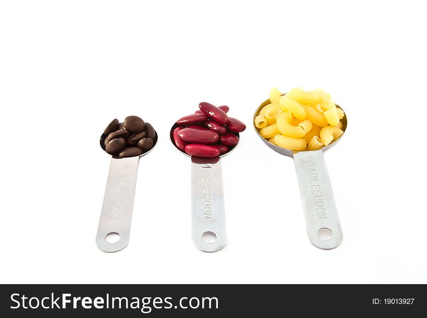 Coffee rad beans and macaroni, measure spoon on white background