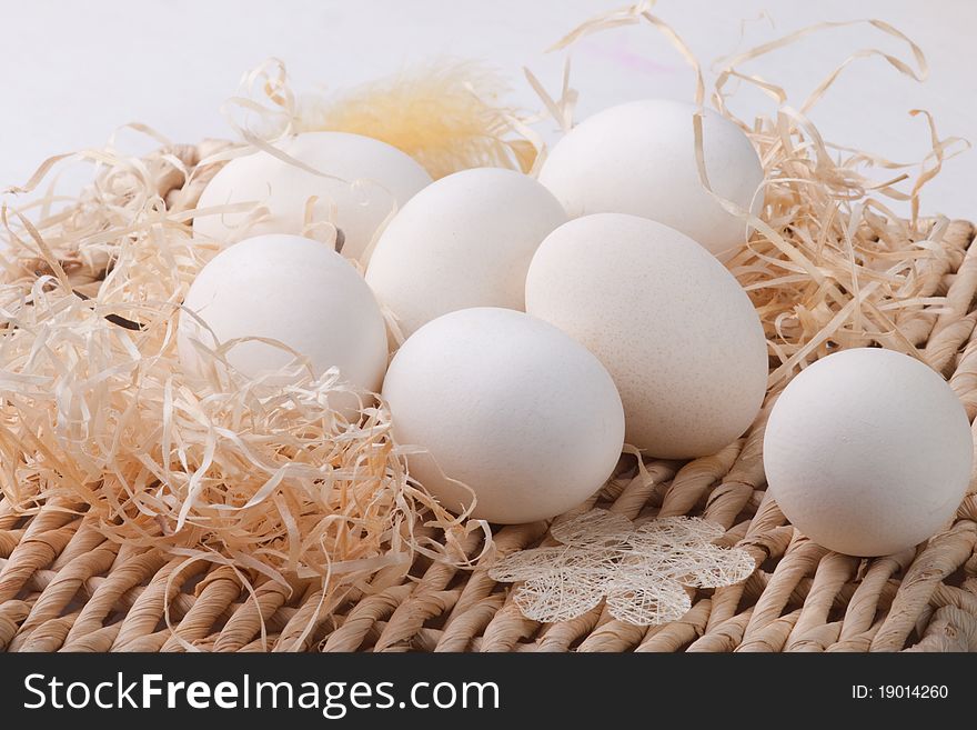 Seven white eggs lying on straw base