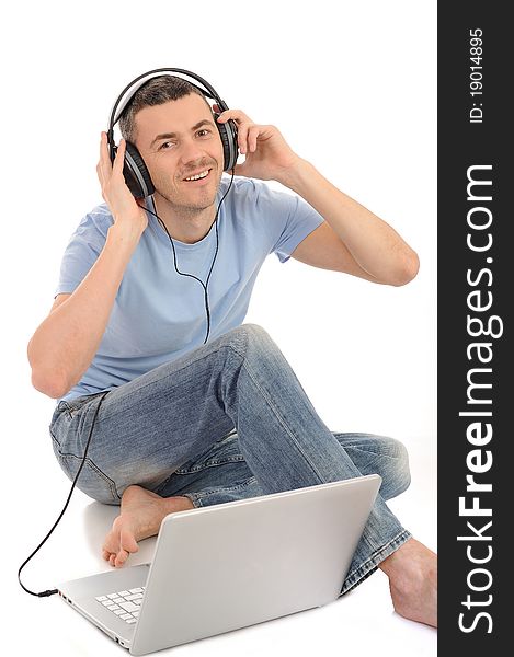 Young handsome man listening to music in headphones from computer. isolated. Young handsome man listening to music in headphones from computer. isolated