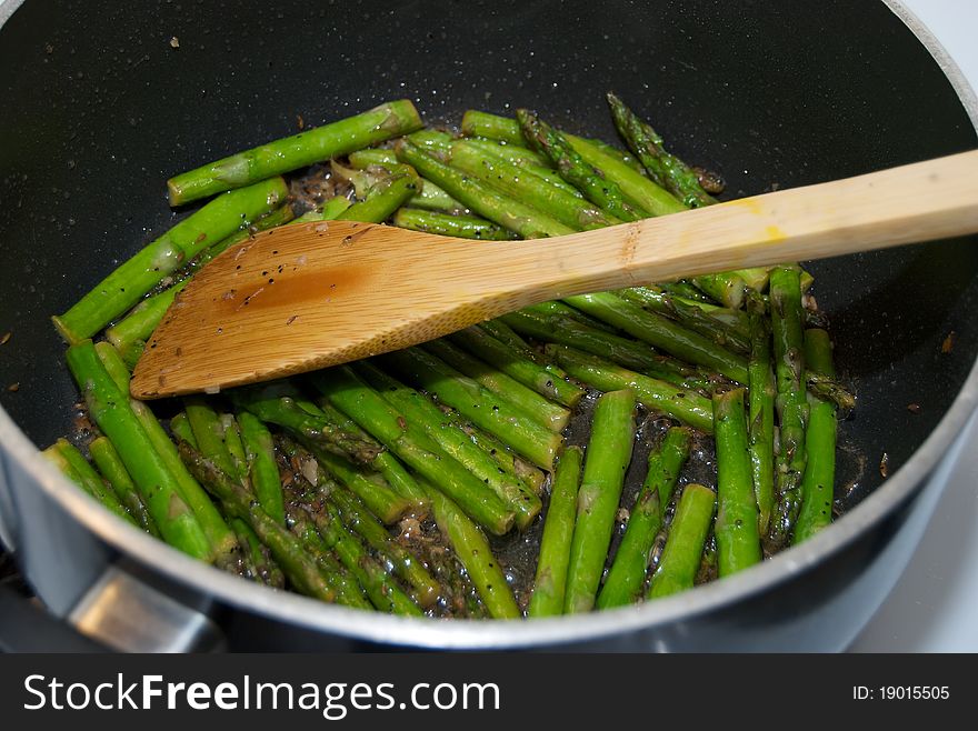 Asparagus being cooked in a pot with spices and bamboo utensil. Asparagus being cooked in a pot with spices and bamboo utensil