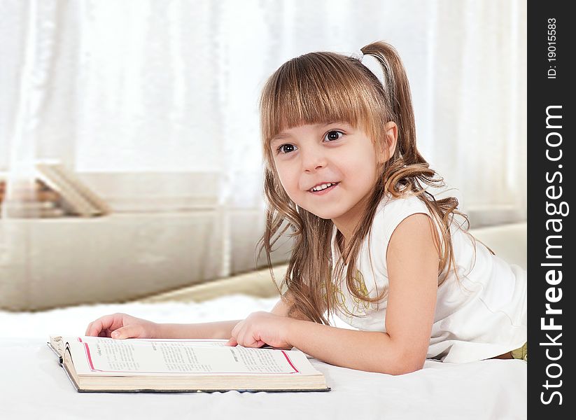 Lovely little girl, reading a book, on the bed. Lovely little girl, reading a book, on the bed