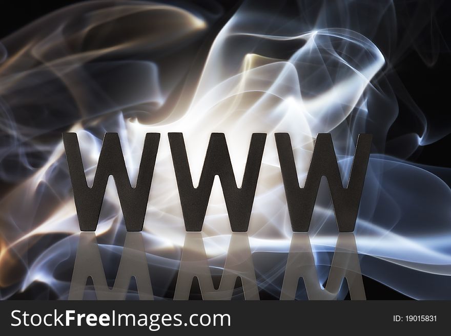 Three black wooden W alphabetic letters with reflection symbolizing the internet and blue orange smoke formation in background. Three black wooden W alphabetic letters with reflection symbolizing the internet and blue orange smoke formation in background.