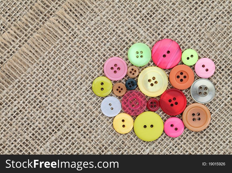 Colorful buttons on burlap background