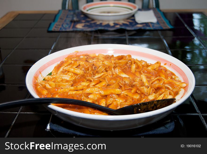 Cavatelli with an Italian Calamari Sauce in a serving dish on a black tile table. Cavatelli with an Italian Calamari Sauce in a serving dish on a black tile table.