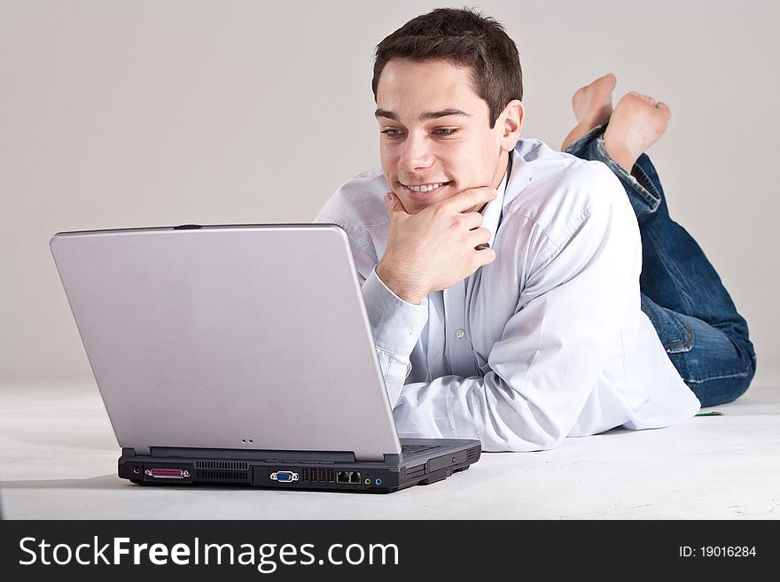 Young man lying on the floor working on his laptop. Young man lying on the floor working on his laptop.