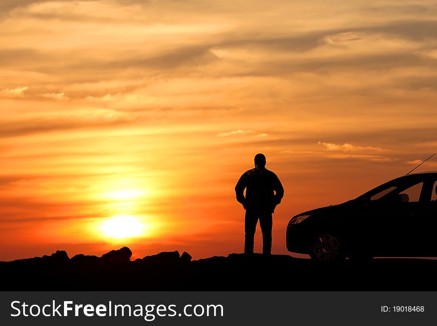 Silhouette of the man standing near to car and looking at a sunset. Silhouette of the man standing near to car and looking at a sunset