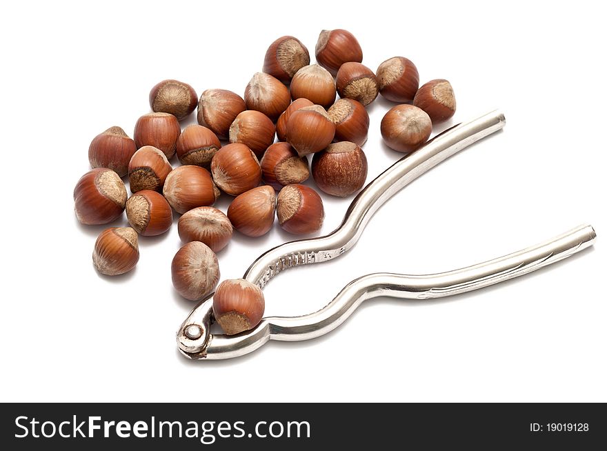 Hazelnuts with nutcracker over a white background