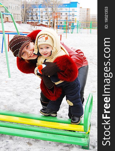 Mother and baby on the playground in winter. Mother and baby on the playground in winter