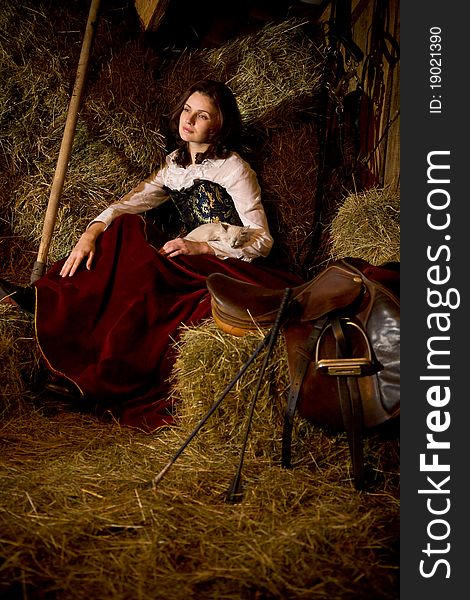 Horsewoman with a kitten on the haystack