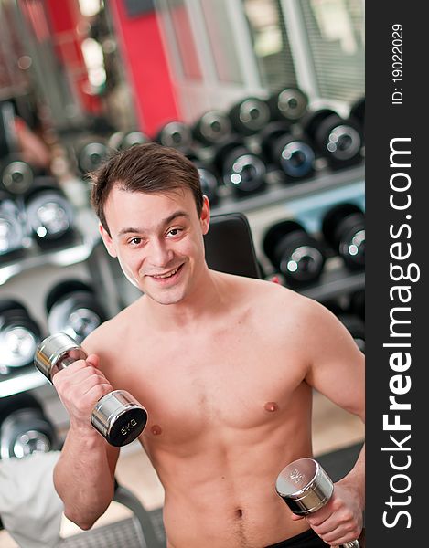 Young man lifting bumbbell in sport club
