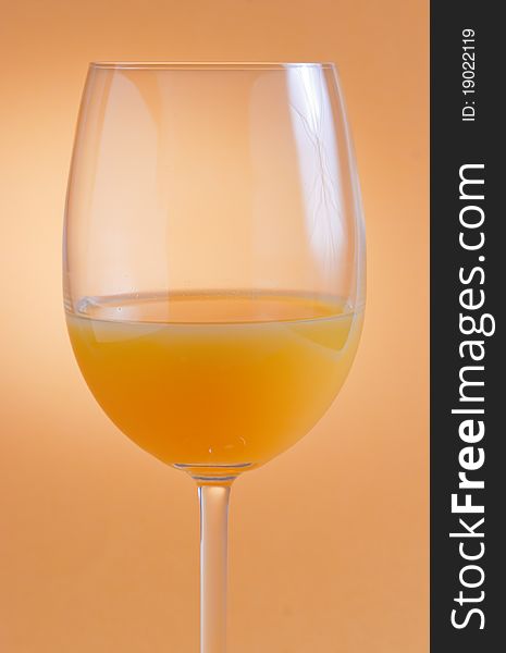 A glass of orange juice on orange background