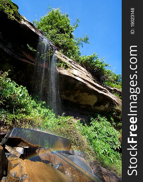 Waterfall in tropical rainforest with rainbow.