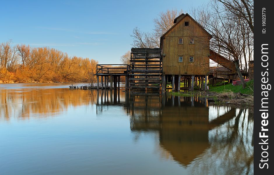 Historic wooden watermill with reflection.