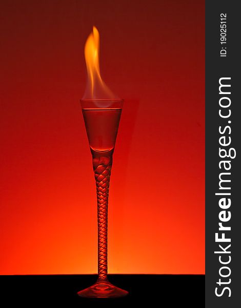 Alcohol burning in beautiful handmade glass with burning red background. Alcohol burning in beautiful handmade glass with burning red background