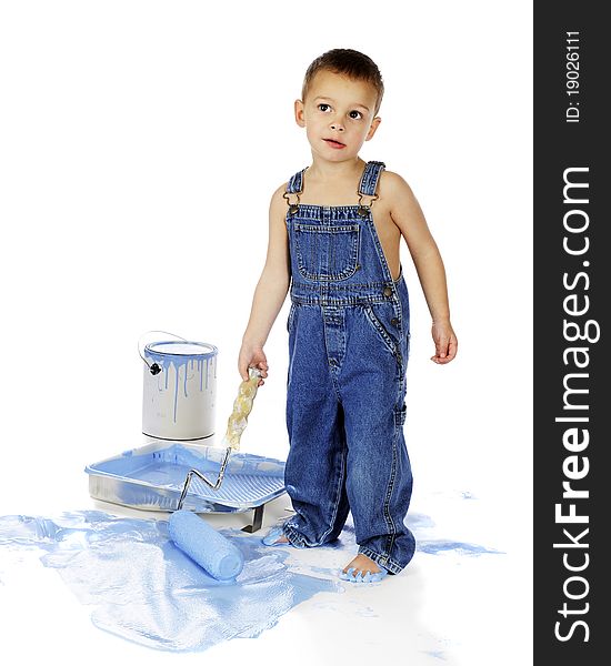 An adorable preschool boy in overalls, giving a quizical look as he uses a roller full of blue paint on the floor. Isolated on white. An adorable preschool boy in overalls, giving a quizical look as he uses a roller full of blue paint on the floor. Isolated on white.