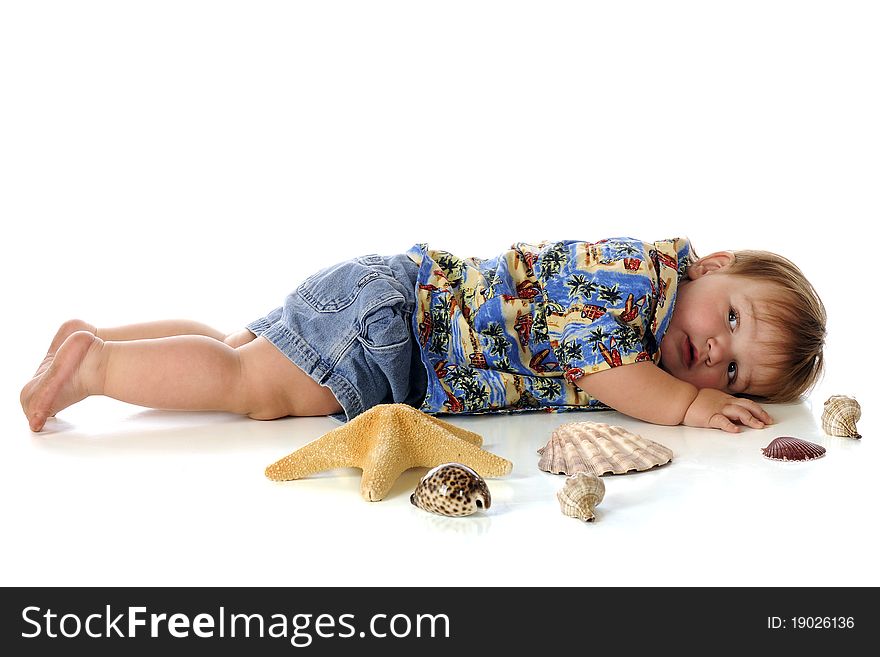 A chubby baby boy in a Hawaiian shirt and shorts, laying flat-out on his belly among sea shells. Isolated on white. A chubby baby boy in a Hawaiian shirt and shorts, laying flat-out on his belly among sea shells. Isolated on white.