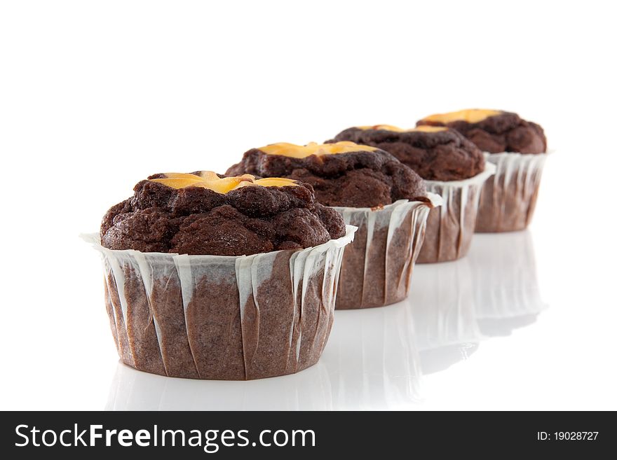 Four tasteful chocolate muffins with yellow colored cake on top isolated over white
